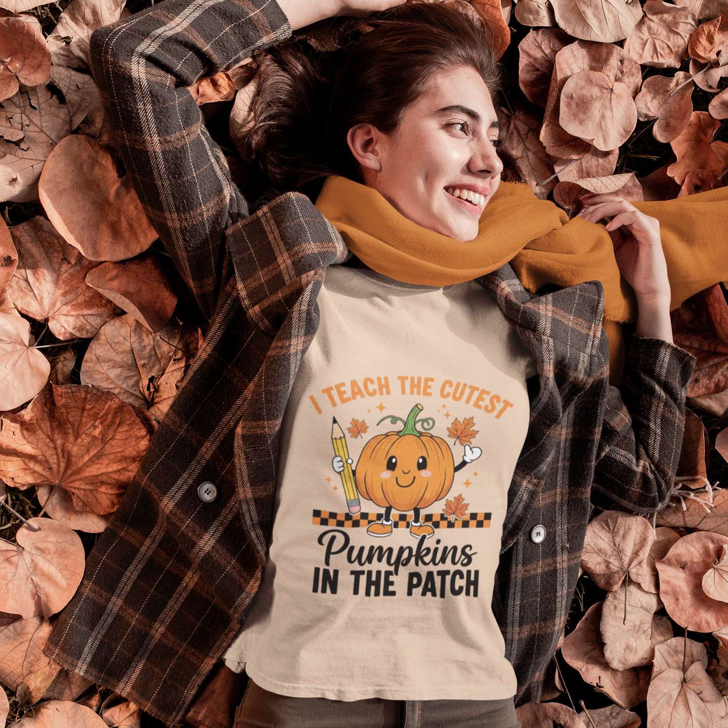 Woman wearing a beige cute fall teacher tee that says “I Teach The Cutest Pumpkins In The Patch.
